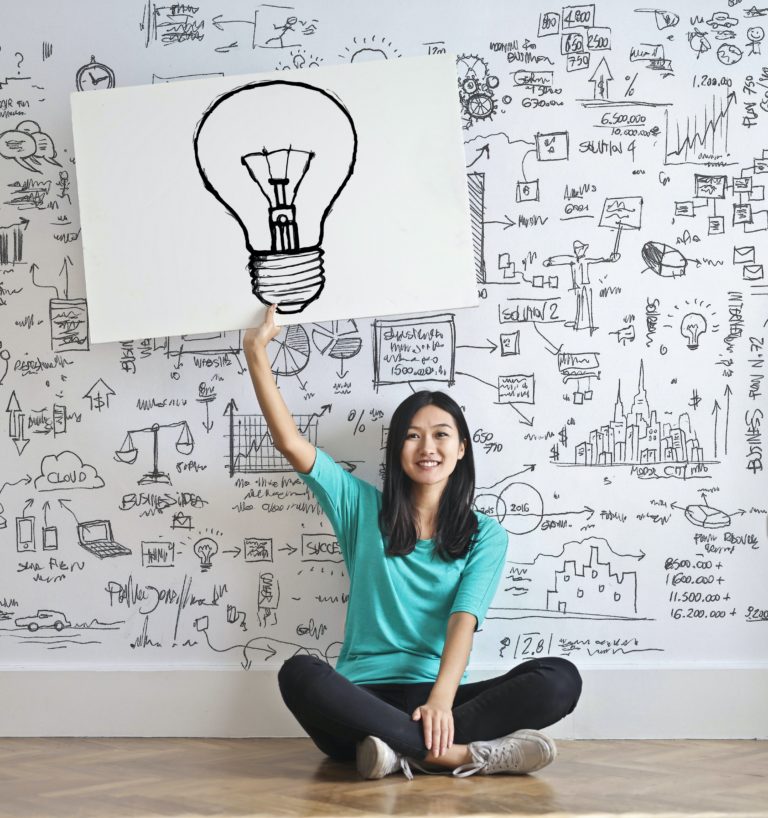 Woman holding a light bulb on a sign sitting down