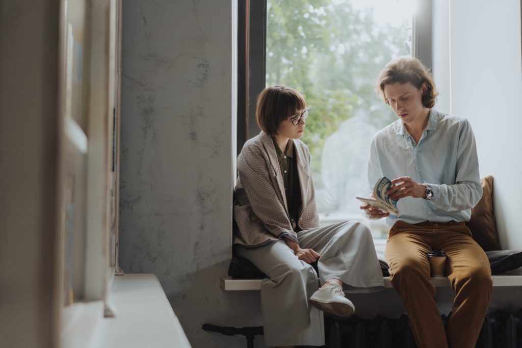 two people reading a book by the window