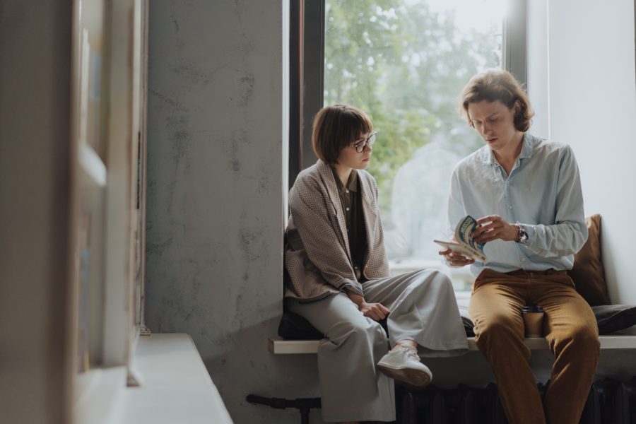 two people reading a book by the window